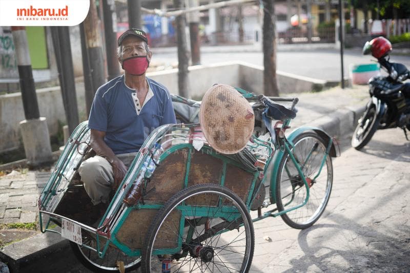 Seorang tukang becak beristirahat di tepi jalan setelah seharian belum mendapat penumpang. (Inibaru.id/ Bayu N)