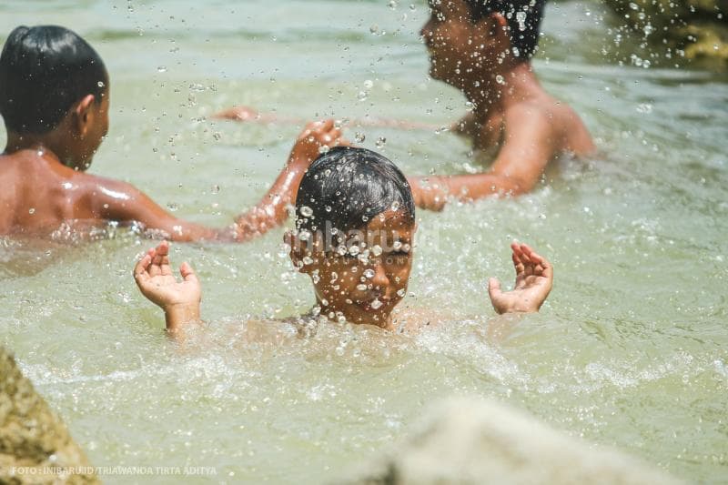 Anak-anak asyik bermain air di sungai ini.