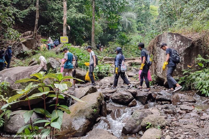 Sembari membawa karung sampah, para sukarelawan berjalan kaki sejauh sekitar satu kilometer menyusuri sungai dan hutan untuk sampai ke Curug Semirang.